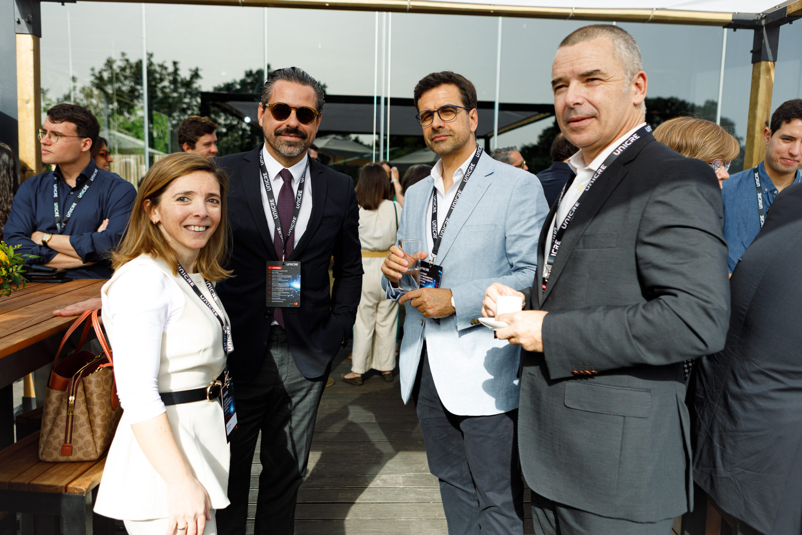 Group of professionally dressed adults with lanyards at an outdoor networking event, smiling for the camera.